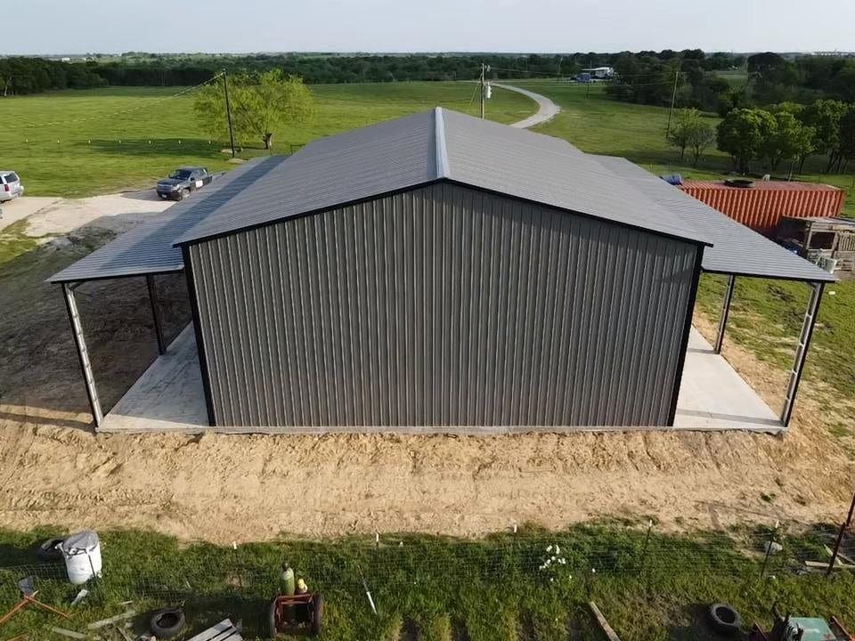 A steel equipment barn with open lean-tos down both sides